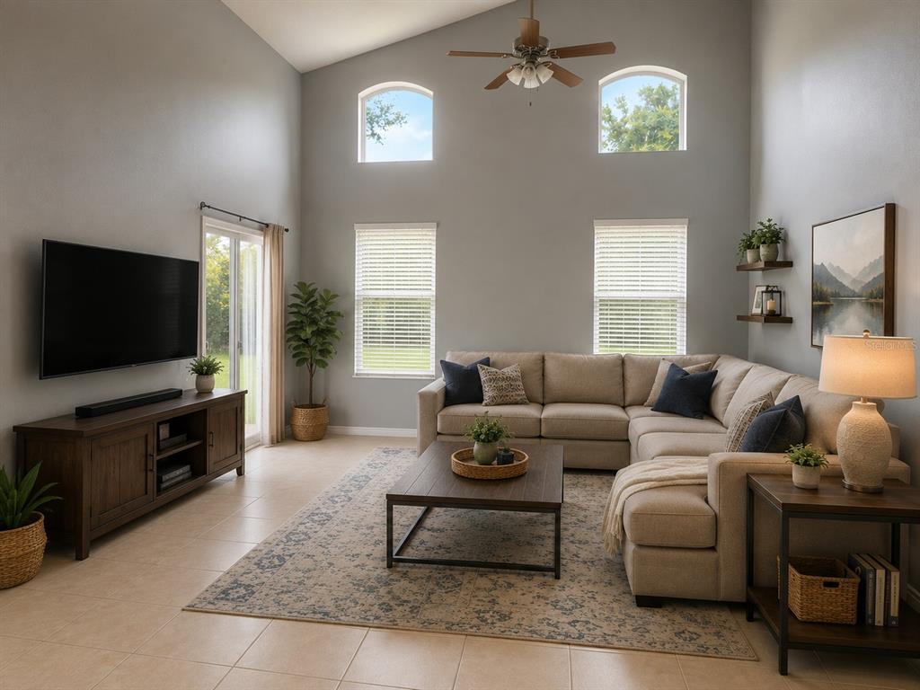 A living room features a sectional sofa, a television, and high ceilings with arched windows — 4406 OLYMPIA COURT, CLERMONT, FL