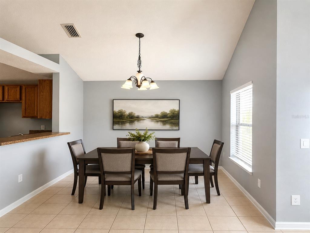 A dining room features a dark wood table with six chairs under a chandelier — 4406 OLYMPIA COURT, CLERMONT, FL