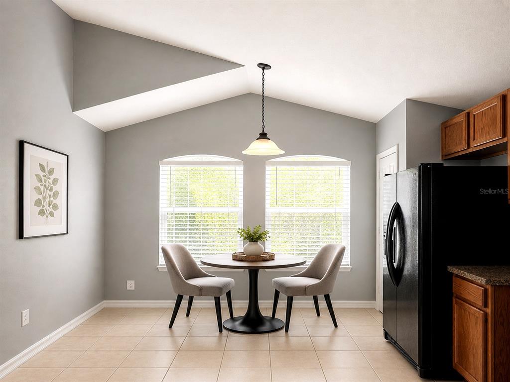 A dining area features a vaulted ceiling, tile flooring, two windows, and a round table — 4406 OLYMPIA COURT, CLERMONT, FL