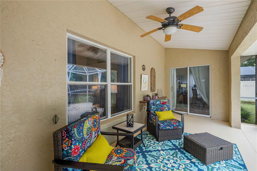 A covered patio features a ceiling fan, colorful patterned furniture, and a blue area rug — 1363 SE 65TH CIRCLE, OCALA, FL