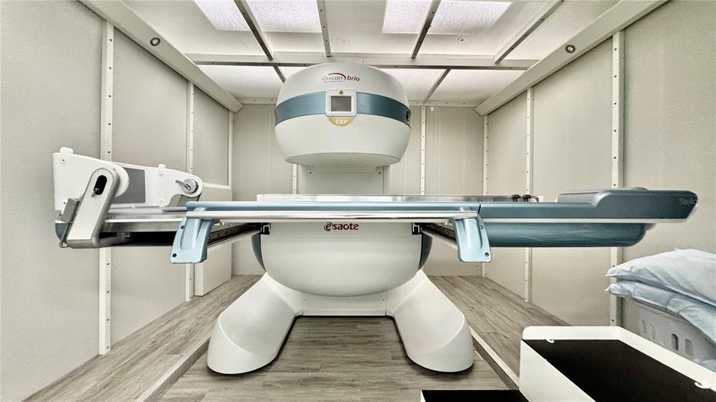 This room contains an Esaote G-scan Brio MRI machine with a patient table and wood flooring — 2301 STATE ROAD 524 UNIT A135, COCOA, FL