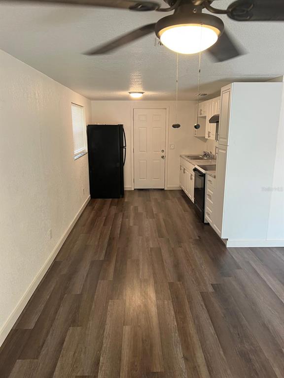 A kitchen with white cabinets, a black refrigerator, and wood-look flooring — 10702 N 14TH STREET UNIT 2, TAMPA, FL