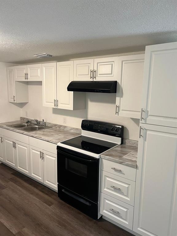A kitchen features white cabinets, a black stove, a black range hood, and laminate countertops — 10702 N 14TH STREET UNIT 2, TAMPA, FL