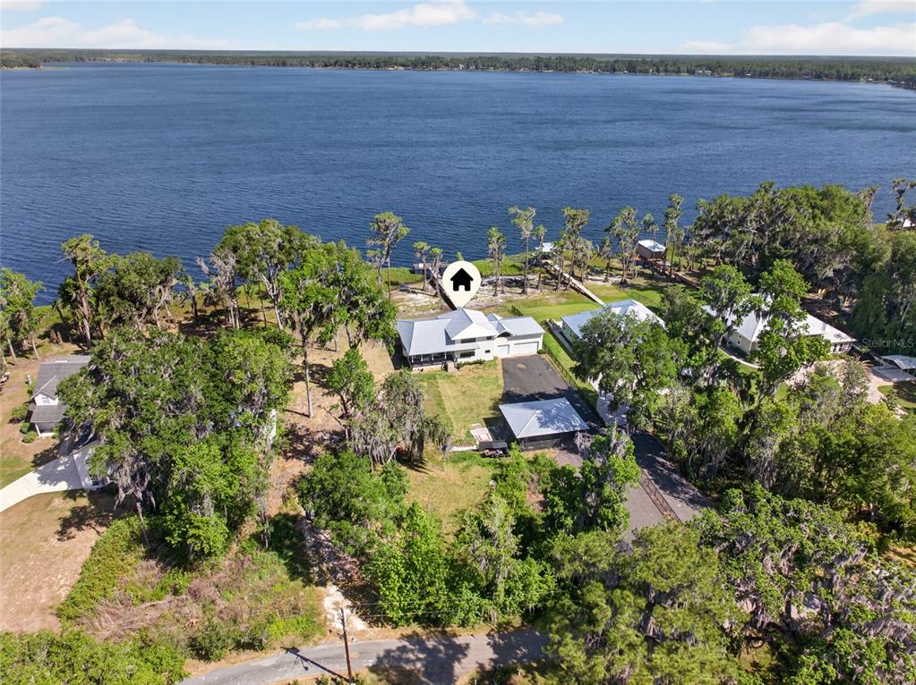 An aerial view shows a house with a metal roof situated on a lakefront lot — 2473 SE 30TH STREET, MELROSE, FL
