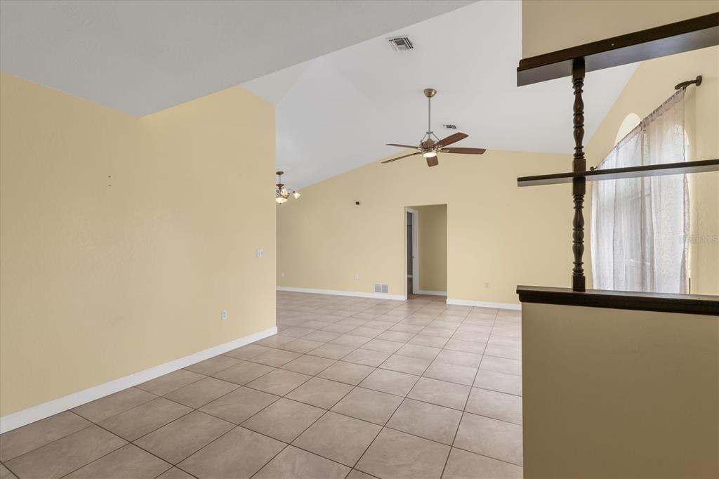 An open-concept living area features light yellow walls, vaulted ceilings, and neutral tile flooring — 10033 STONECROP AVENUE, ENGLEWOOD, FL
