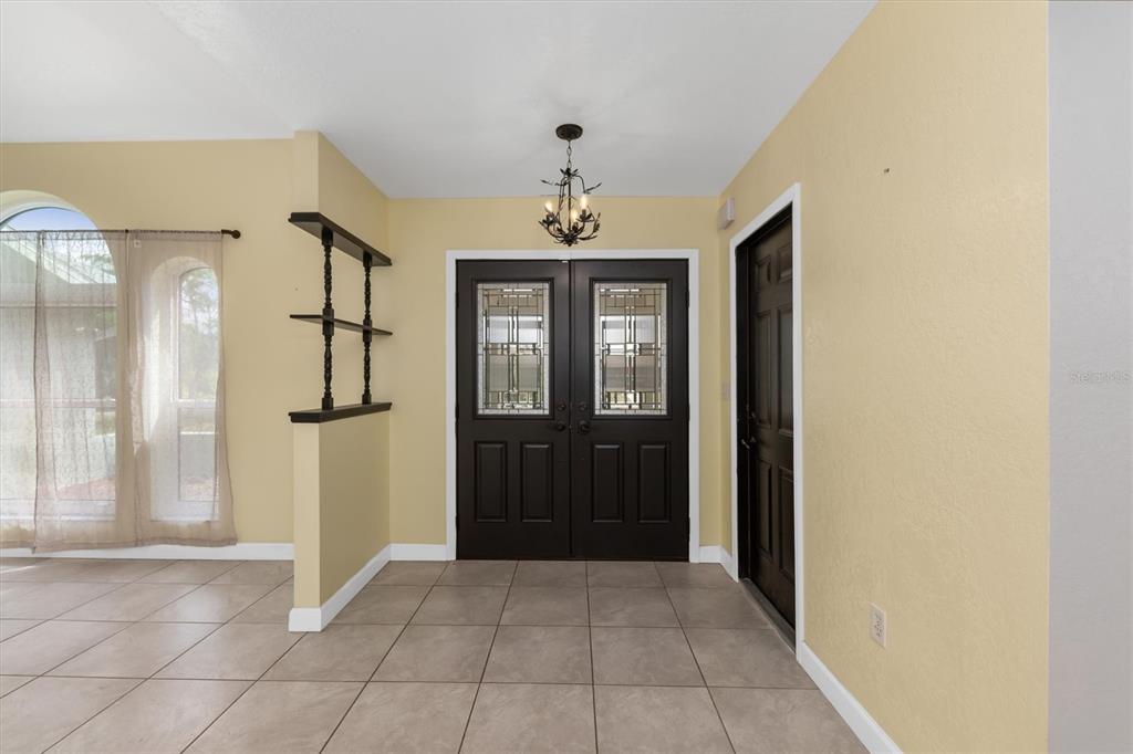 An entryway features tile flooring, a dark double front door, and a small chandelier — 10033 STONECROP AVENUE, ENGLEWOOD, FL