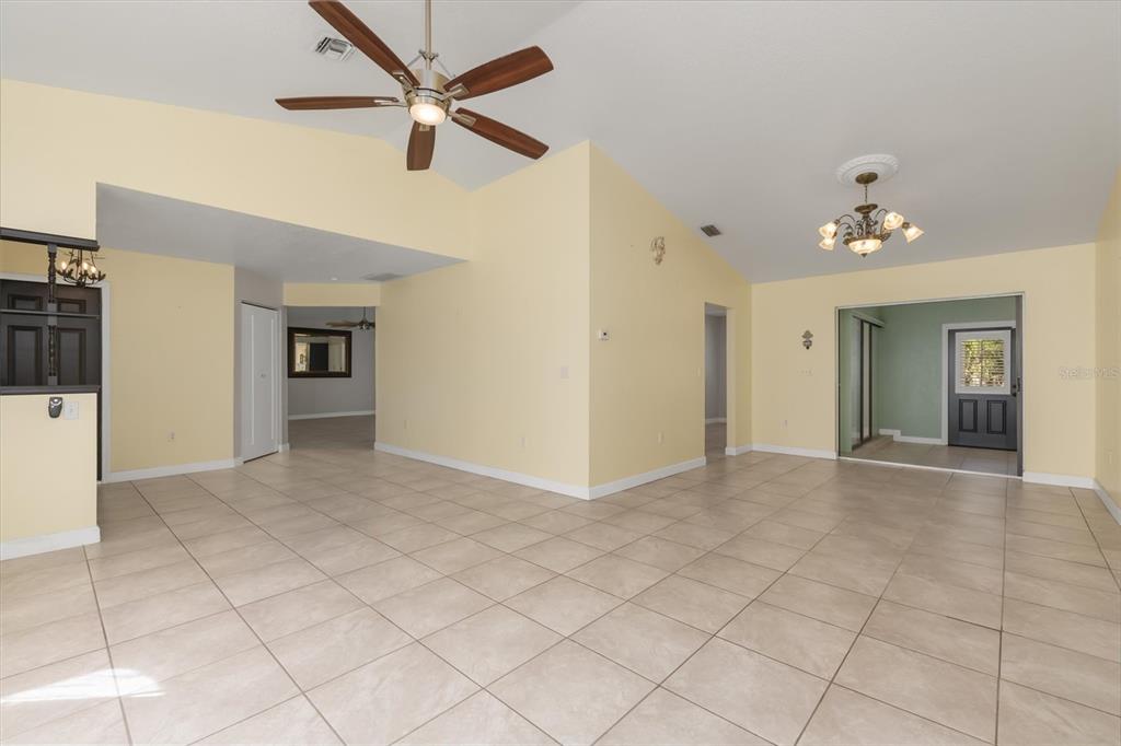 A spacious living area features light yellow walls, tile flooring, and a vaulted ceiling — 10033 STONECROP AVENUE, ENGLEWOOD, FL