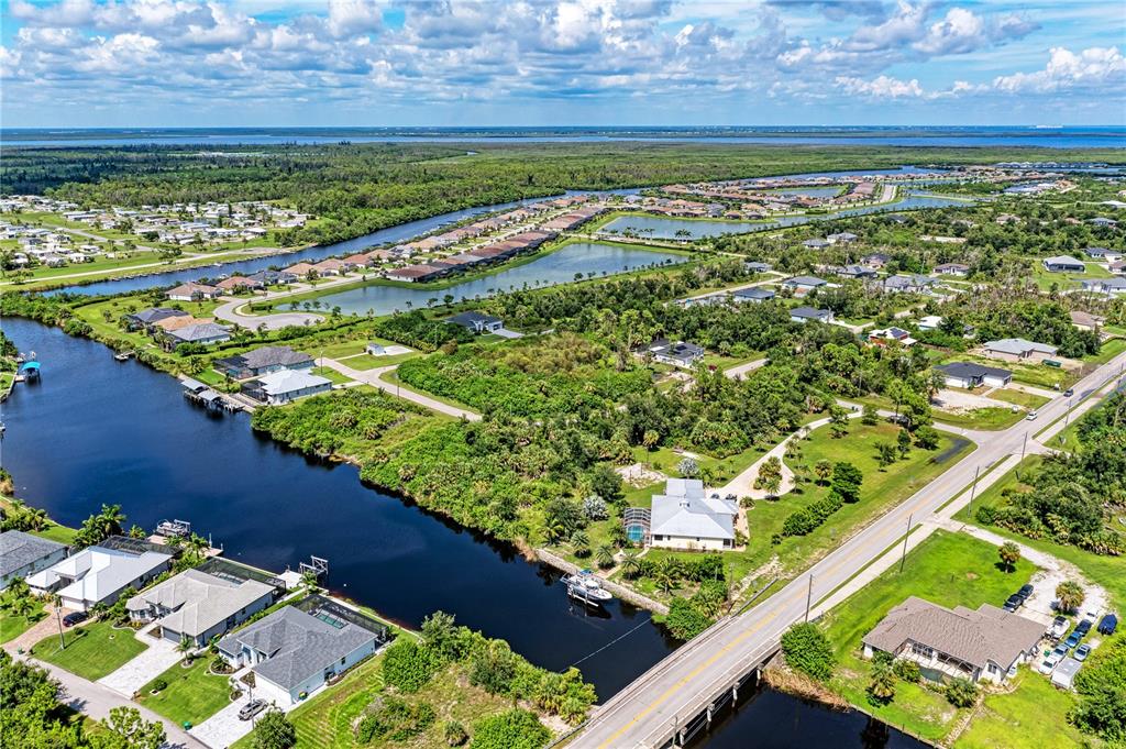 An aerial view shows residential homes along a canal with a bridge and surrounding vegetation — 14284 HUMBOLD ROAD, PORT CHARLOTTE, FL