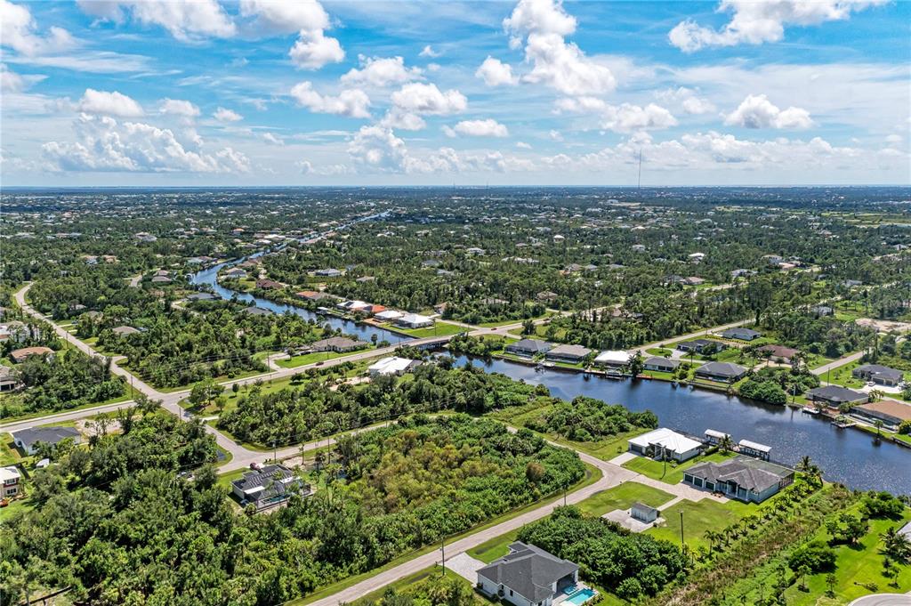 An aerial view shows a canal winding through a residential neighborhood with lush green vegetation — 14284 HUMBOLD ROAD, PORT CHARLOTTE, FL