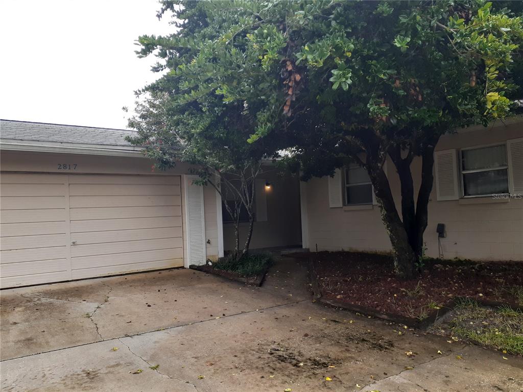 A single-story house with a beige garage, a concrete driveway, and a large shade tree — 2817 BOWER ROAD, WINTER PARK, FL