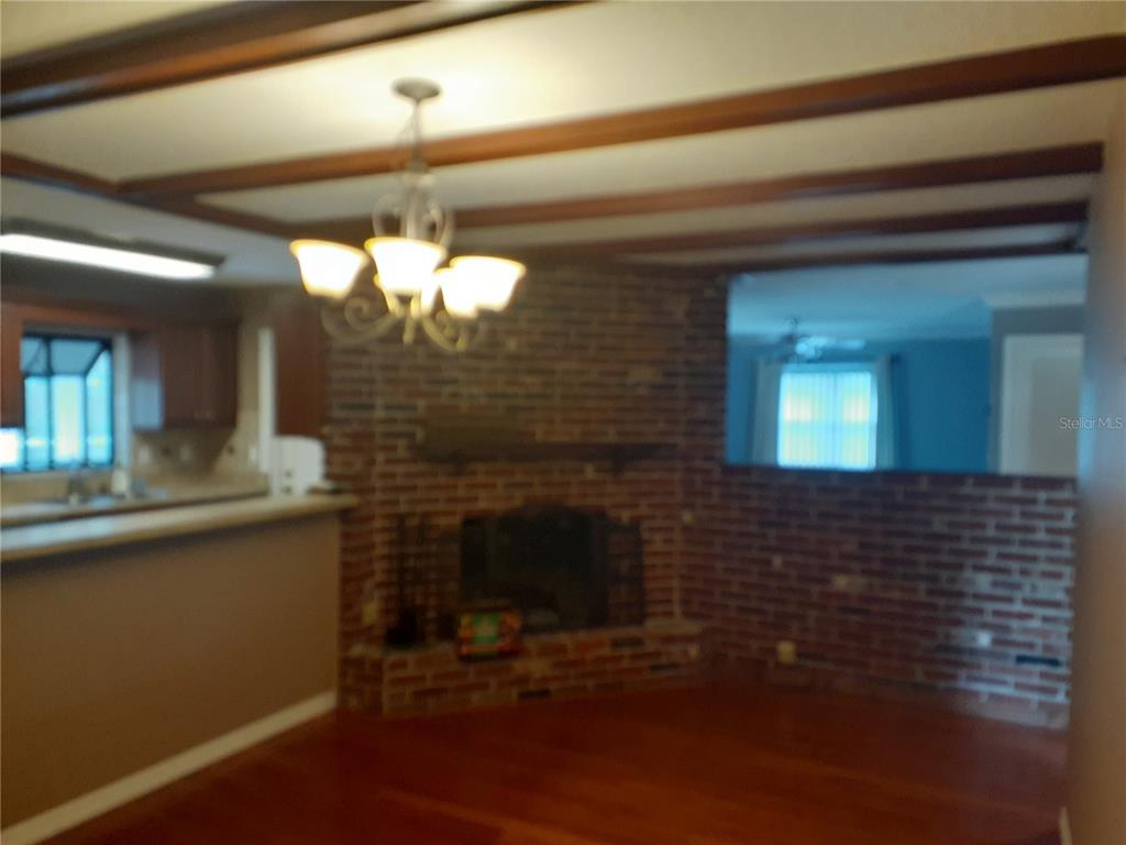 A living room features a brick fireplace, wood ceiling beams, and hardwood flooring — 2817 BOWER ROAD, WINTER PARK, FL