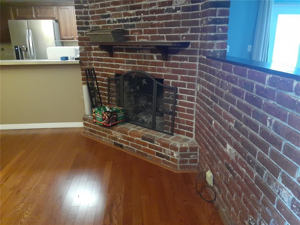 A brick fireplace with a wooden mantel sits in a room with hardwood flooring — 2817 BOWER ROAD, WINTER PARK, FL