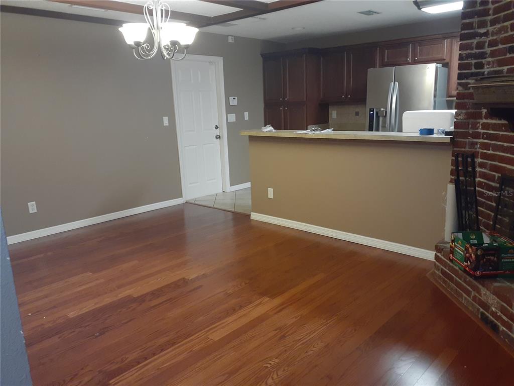A dining area with hardwood floors, a chandelier, and a breakfast bar overlooking the kitchen — 2817 BOWER ROAD, WINTER PARK, FL