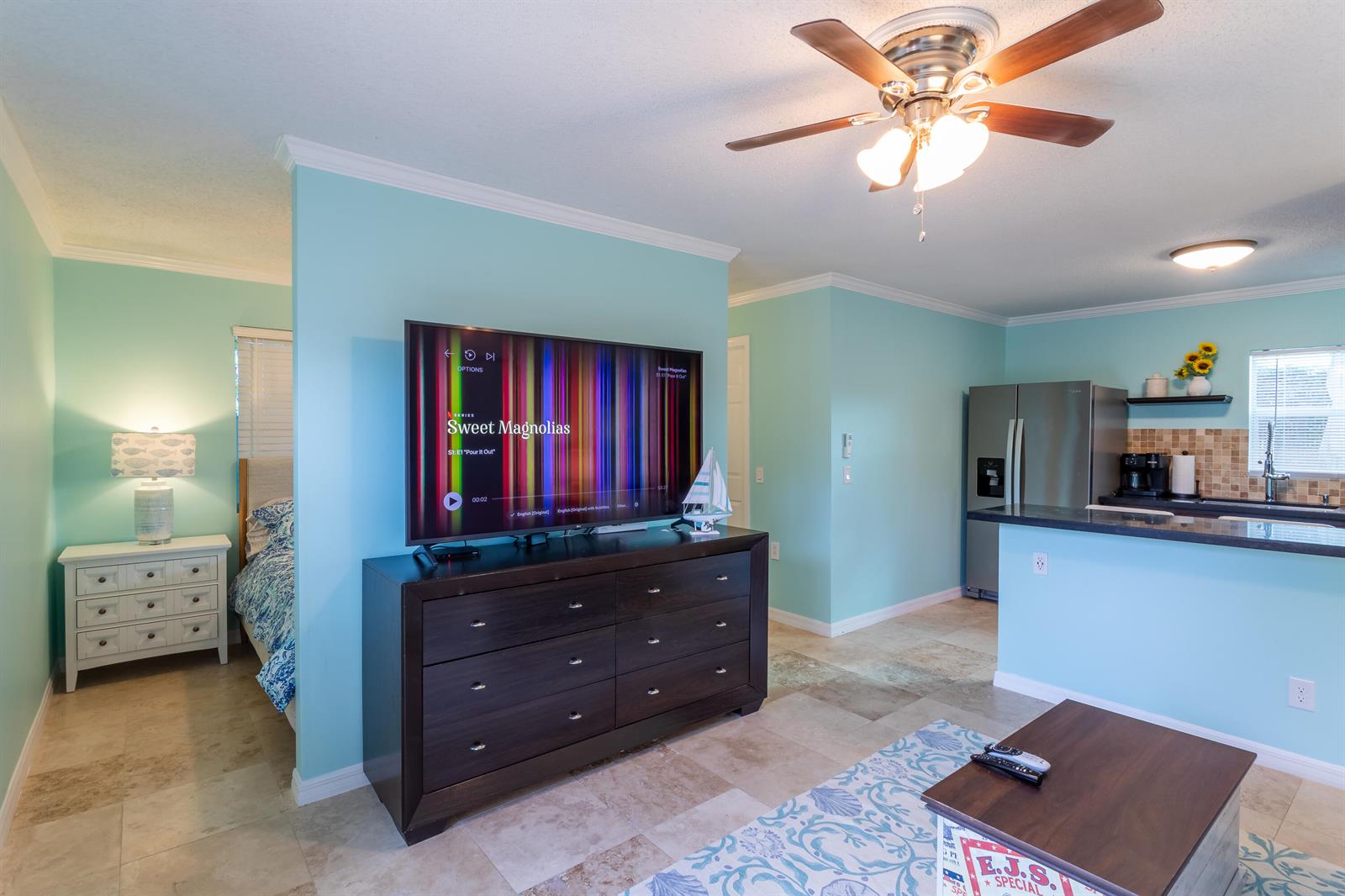 A living room with a dark wood dresser and television, adjacent to a kitchen and bedroom — 1724 37th Street, West Palm Beach FL 33407, WEST PALM BEACH, FL