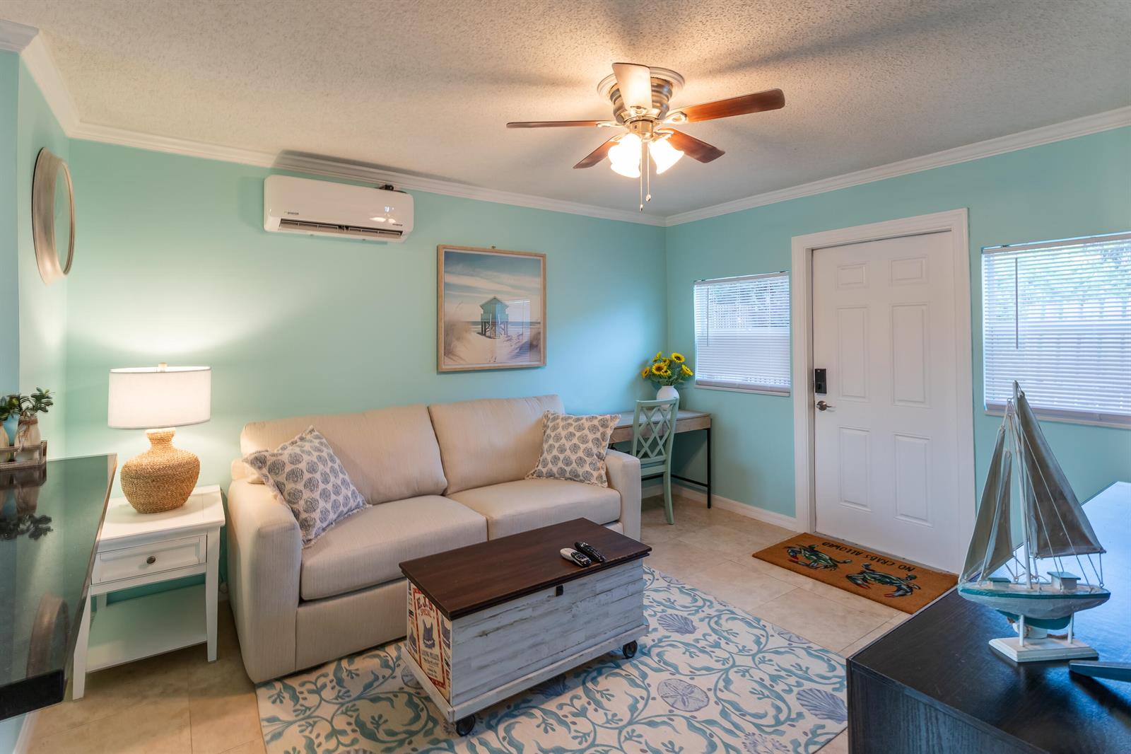 A living room features a beige sofa, a coffee table, a ceiling fan, and light-blue walls — 1724 37th Street, West Palm Beach FL 33407, WEST PALM BEACH, FL