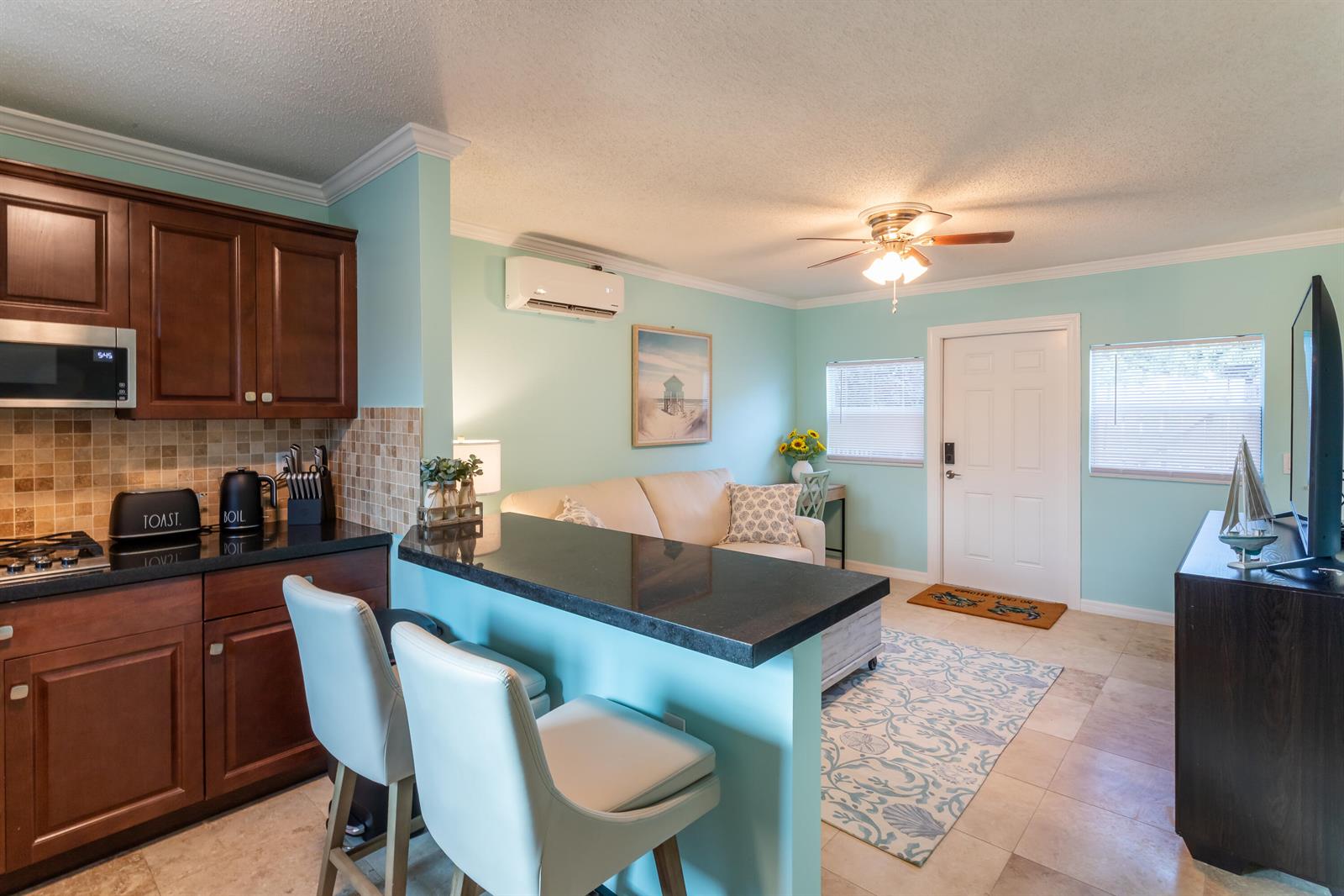 A kitchen with dark cabinets and a breakfast bar opens into a living area — 1724 37th Street, West Palm Beach FL 33407, WEST PALM BEACH, FL