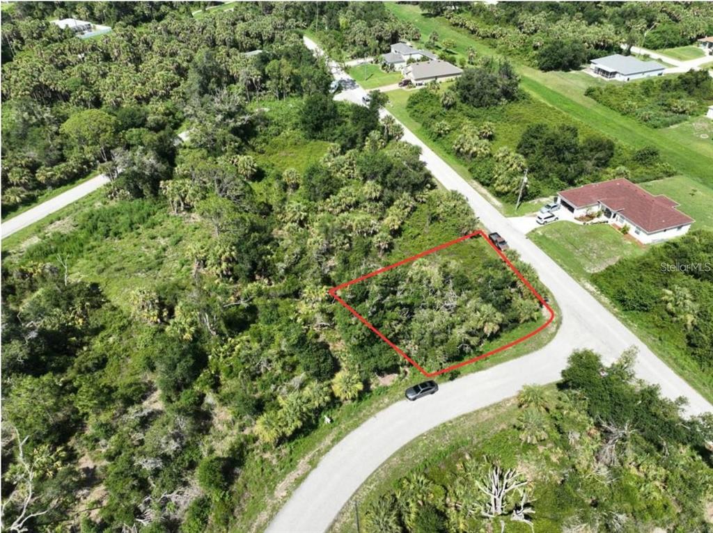 An aerial view shows a vacant, wooded residential lot outlined in red along a paved road — JINRIGHT ROAD, NORTH PORT, FL