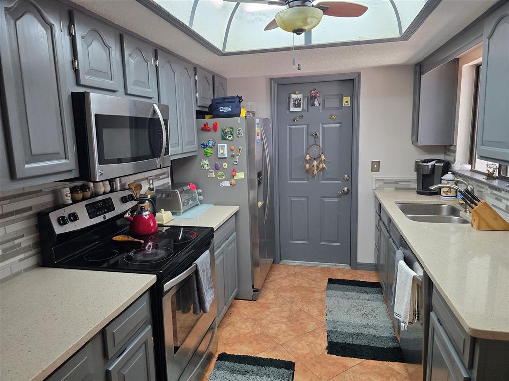 A kitchen features gray cabinets, stainless steel appliances, quartz countertops, and a skylight — 2259 BRANCHWOOD DRIVE, NEW SMYRNA BEACH, FL