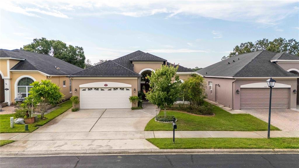 A single-story suburban house with a two-car garage and a landscaped front yard — 935 EKANA GREEN COURT, OVIEDO, FL