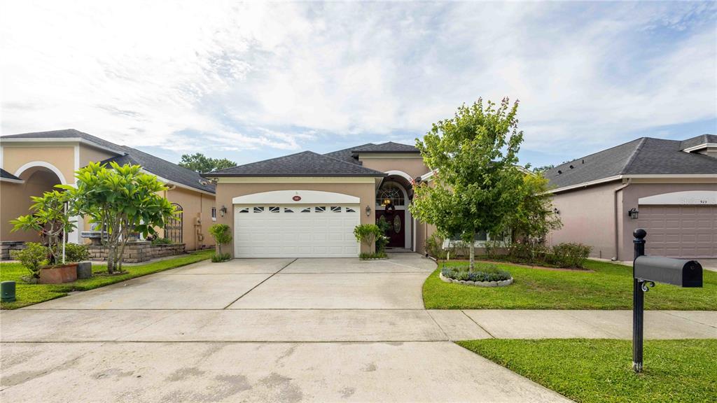 A single-story suburban house with a two-car garage, a concrete driveway, and a front lawn — 935 EKANA GREEN COURT, OVIEDO, FL
