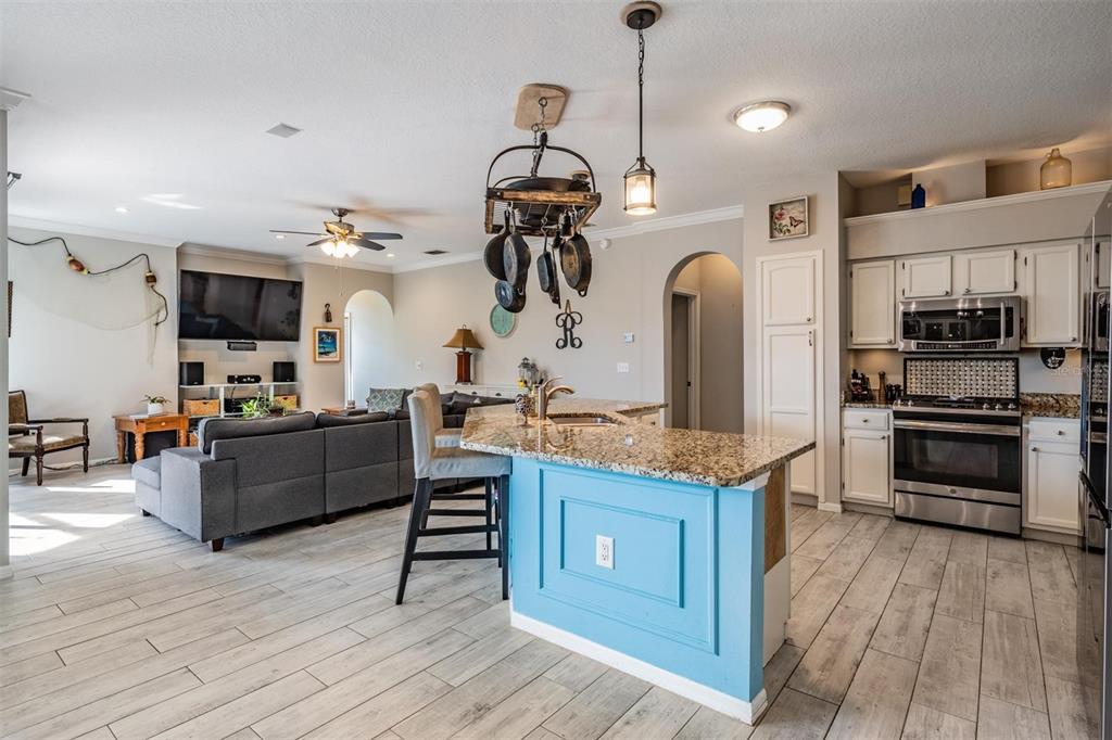 A kitchen with a blue island and granite countertops opens into a living room area — 15922 MUIRFIELD DRIVE, ODESSA, FL