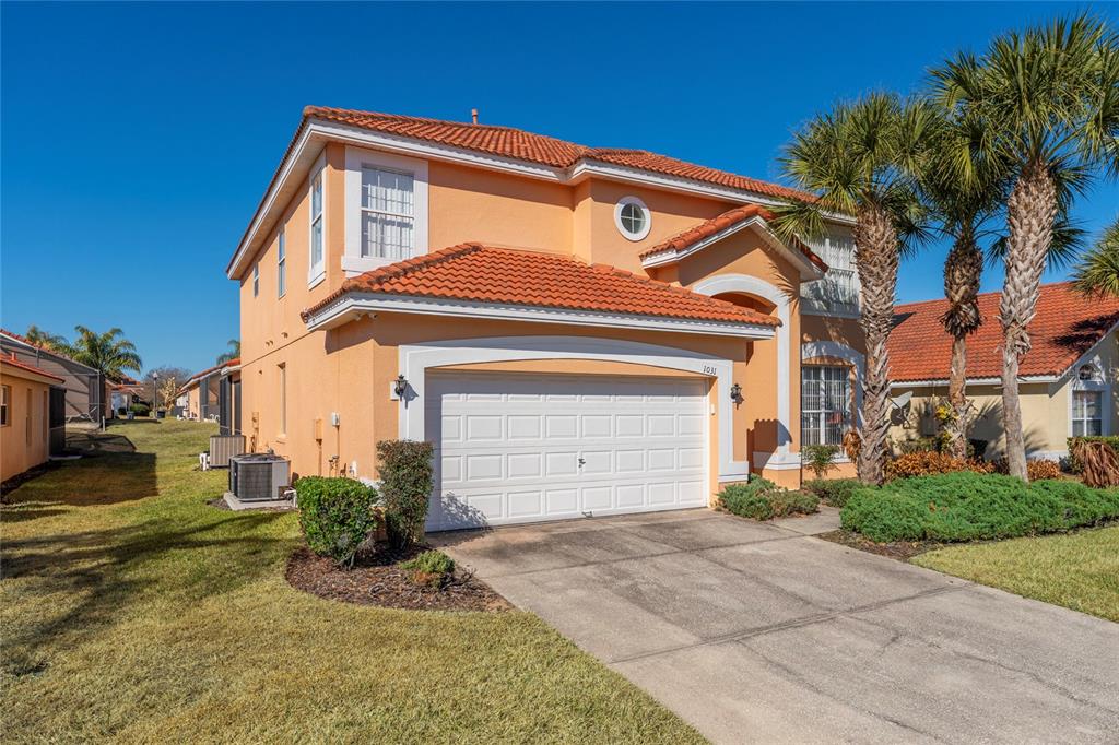 A two-story peach-colored house with a tile roof and a two-car garage — 1031 SOLANA CIRCLE, DAVENPORT, FL
