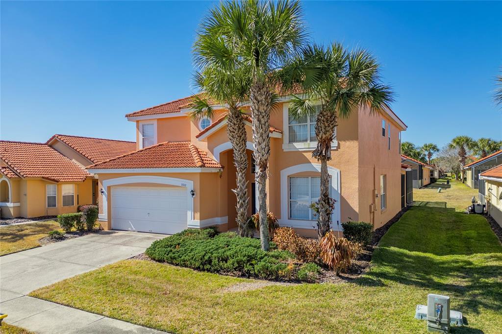 A two-story, orange stucco house with a tiled roof, a garage, and two palm trees — 1031 SOLANA CIRCLE, DAVENPORT, FL