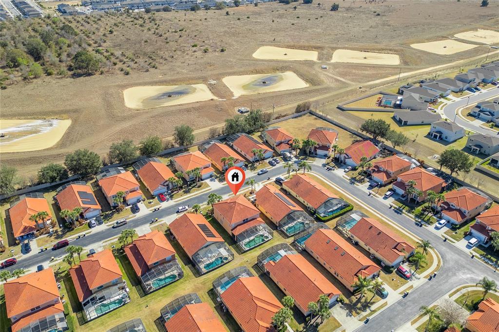 An aerial view shows a suburban neighborhood with houses featuring orange tile roofs and pools — 1031 SOLANA CIRCLE, DAVENPORT, FL
