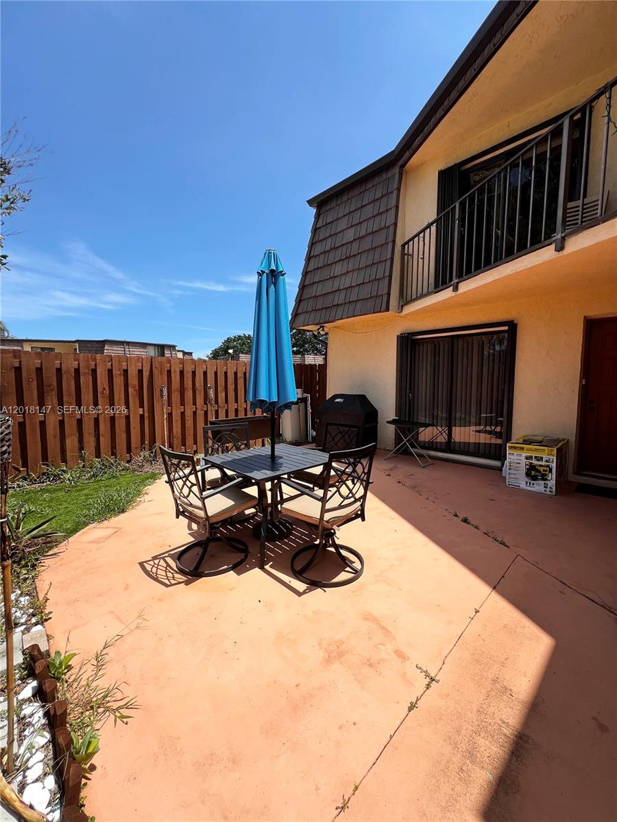 A patio features a dining set with a blue umbrella next to a two-story building — 192 Springdale Cir # 192, Palm Springs FL 33461, PALM SPRINGS, FL