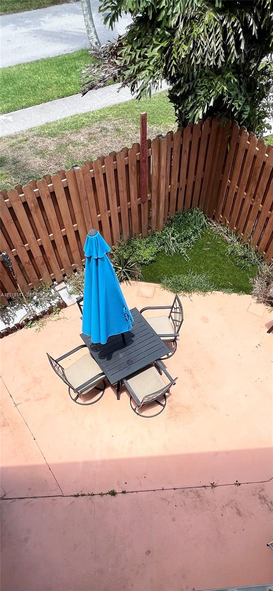 An elevated view of a patio with a table, chairs, blue umbrella, and wooden fence — 192 Springdale Cir # 192, Palm Springs FL 33461, PALM SPRINGS, FL