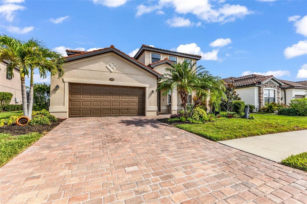 A two-story house with a paved driveway, a brown garage door, and palm trees — 13682 VANCANZA DRIVE, VENICE, FL