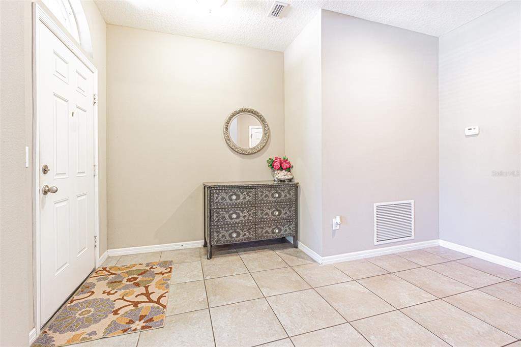 An entryway features beige tile flooring, a white front door, and a decorative wooden chest — 1667 NATURE VIEW DRIVE, LUTZ, FL