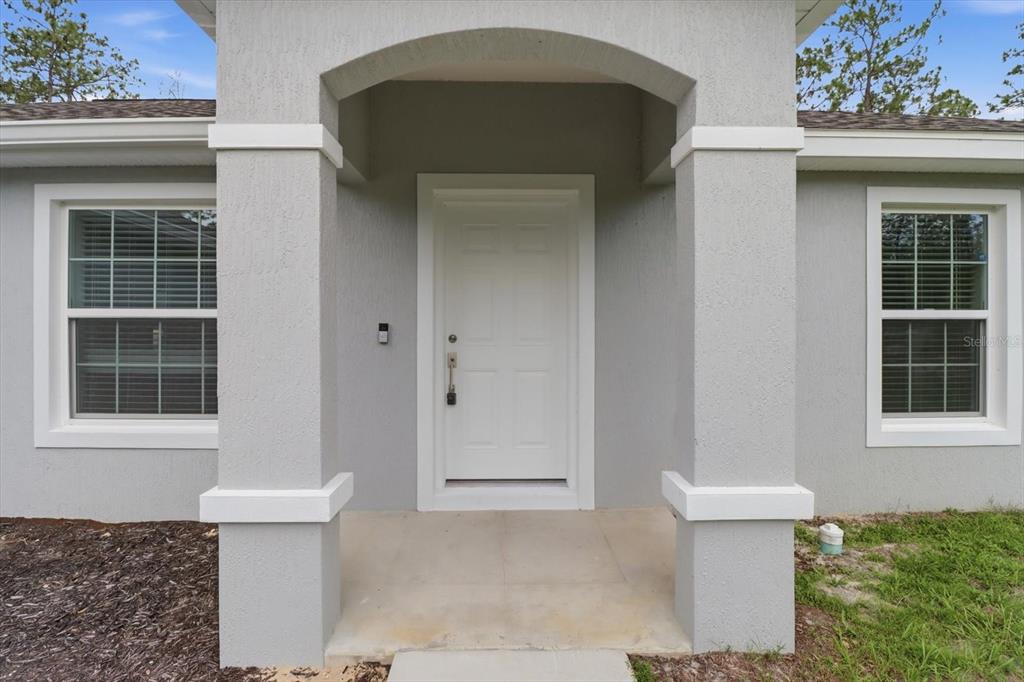 The front entrance of a house features a white door between two gray stucco columns — 3266 SW ADMIRAL LANDING DRIVE, DUNNELLON, FL