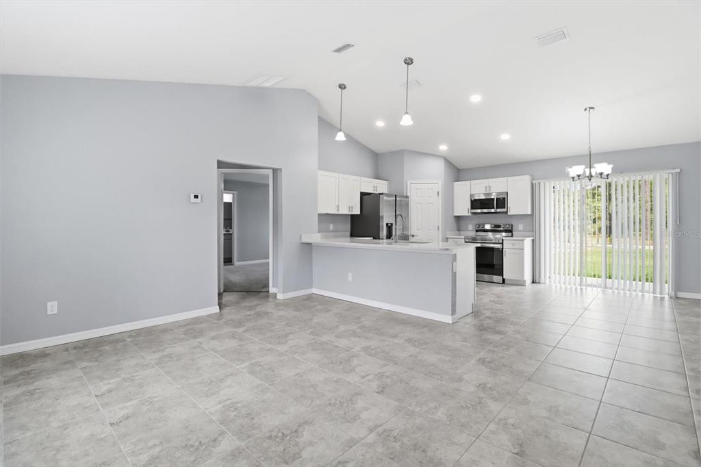 A kitchen with white cabinets and stainless steel appliances opens to a tiled living area — 3266 SW ADMIRAL LANDING DRIVE, DUNNELLON, FL