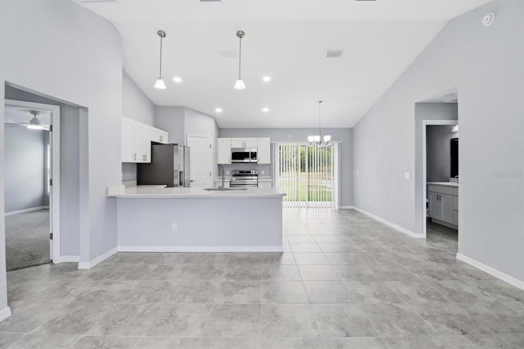A kitchen with white cabinets and a breakfast bar overlooks a tiled living area — 3266 SW ADMIRAL LANDING DRIVE, DUNNELLON, FL