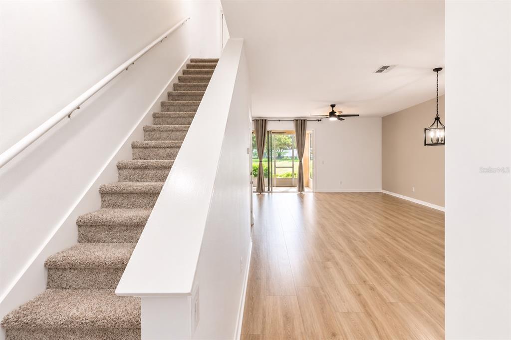A carpeted staircase leads upstairs next to an open living area with wood-look flooring — 1636 W SPRING MEADOW LOOP, LECANTO, FL
