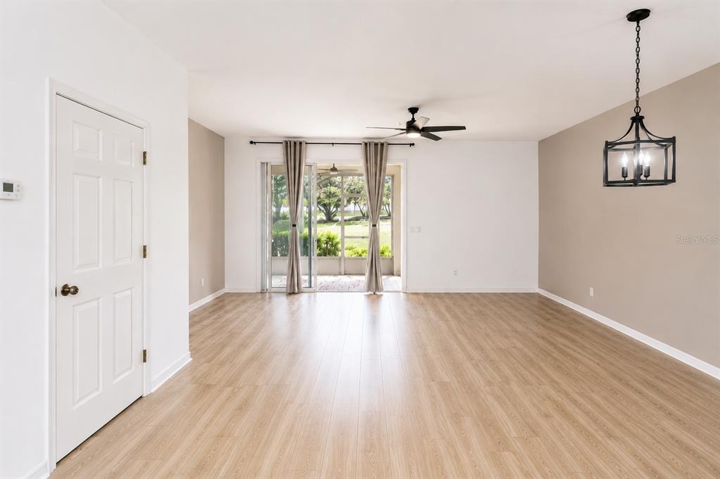 A living room with light wood-look flooring, a ceiling fan, and sliding glass patio doors — 1636 W SPRING MEADOW LOOP, LECANTO, FL