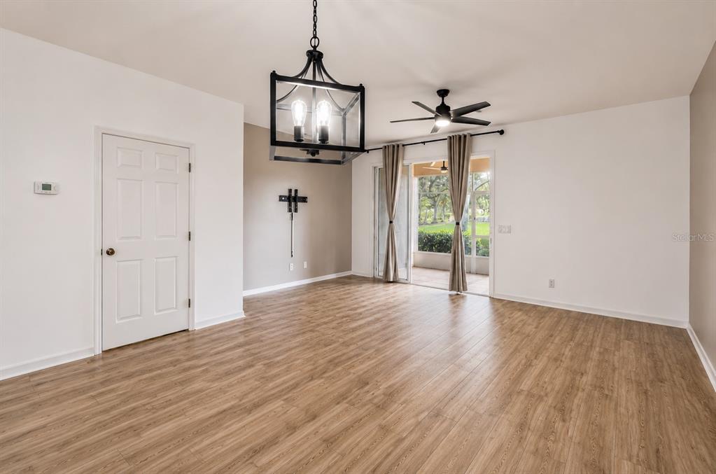 An empty room features wood-look flooring, a black lantern chandelier, and sliding glass patio doors — 1636 W SPRING MEADOW LOOP, LECANTO, FL
