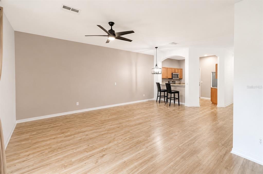 An open-concept living area features light wood-look flooring, a ceiling fan, and a kitchen breakfast bar — 1636 W SPRING MEADOW LOOP, LECANTO, FL