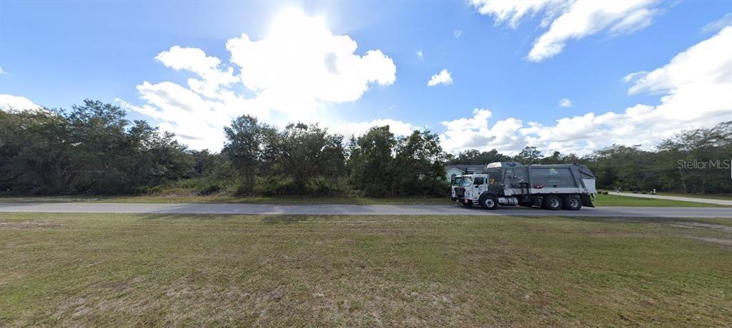 A garbage truck drives along a road in front of a wooded, undeveloped lot — 711 EL DORADO DRIVE, INDIAN LAKE ESTATES, FL