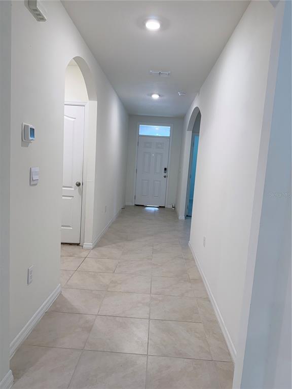 A tiled hallway leads to a white front door with arched entryways on both sides — 1344 SUGARWOOD STREET, DAVENPORT, FL