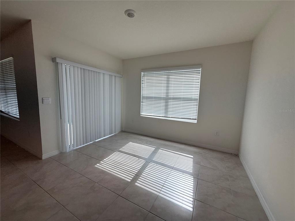 An empty room with tile flooring, a sliding glass door, and a window with blinds — 1344 SUGARWOOD STREET, DAVENPORT, FL