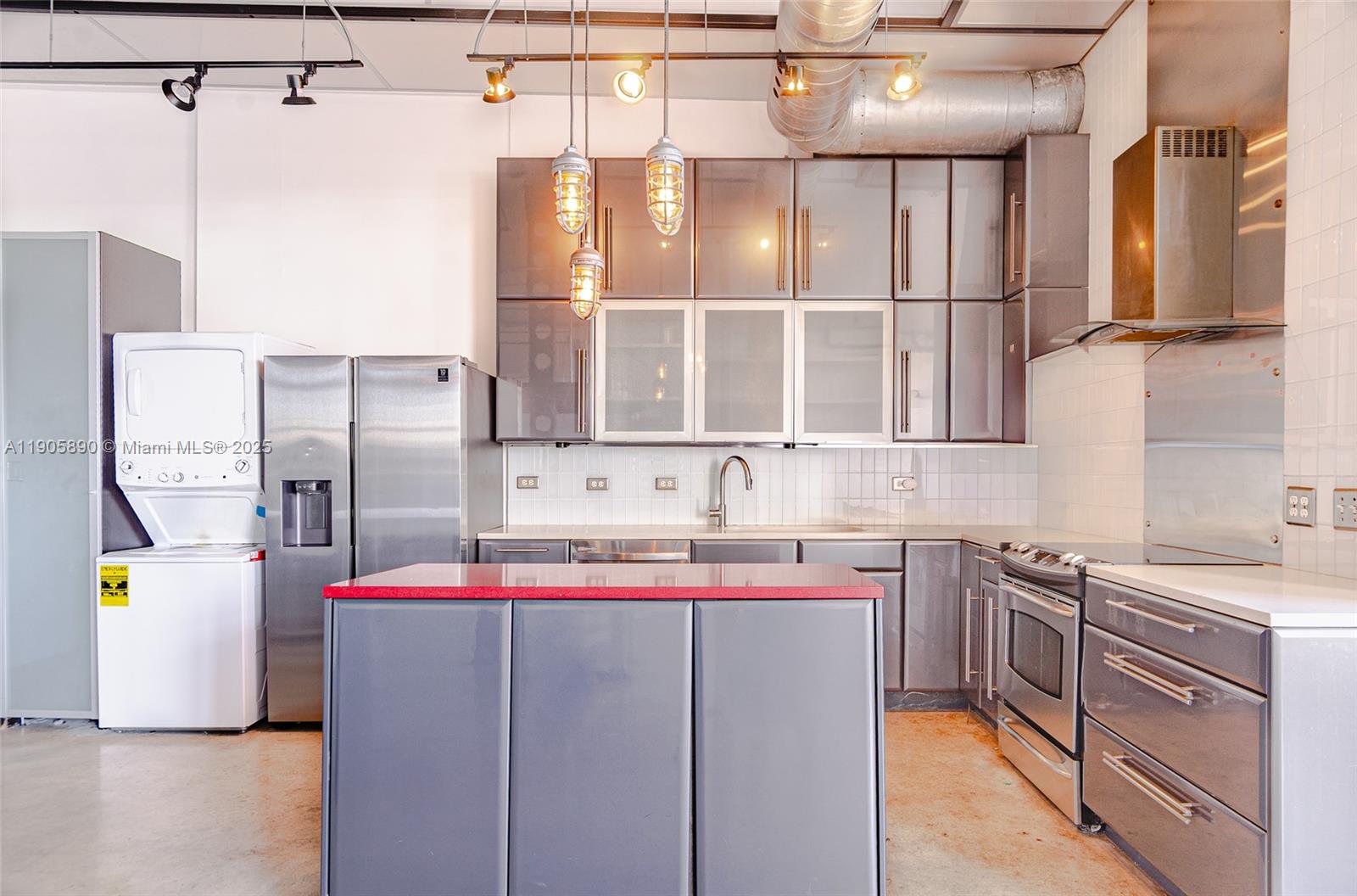 A modern kitchen features gray cabinets, stainless steel appliances, a red island, and industrial lighting — 250 NW 23rd # 405, Miami FL 33127, MIAMI, FL