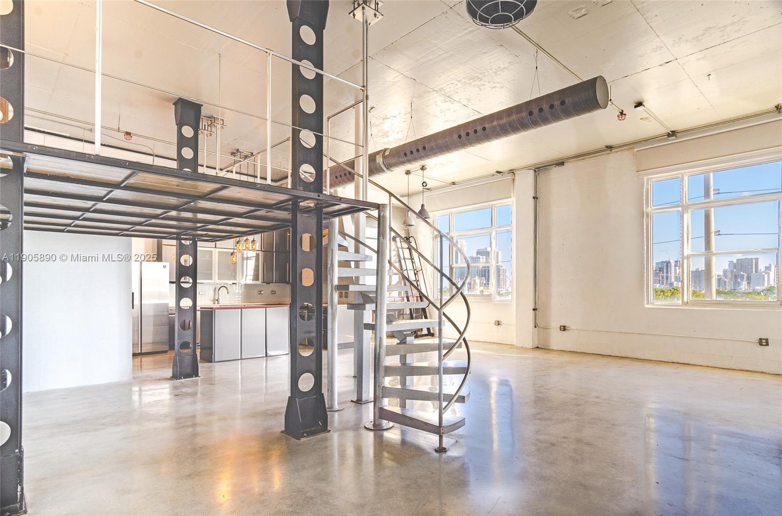 An industrial-style loft features a metal spiral staircase, a mezzanine level, and polished concrete floors — 250 NW 23rd # 405, Miami FL 33127, MIAMI, FL
