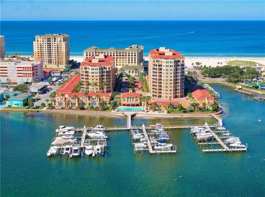 An aerial view of a waterfront resort complex featuring multiple buildings, a pool, and docks — 521 MANDALAY AVENUE UNIT 1109, CLEARWATER BEACH, FL