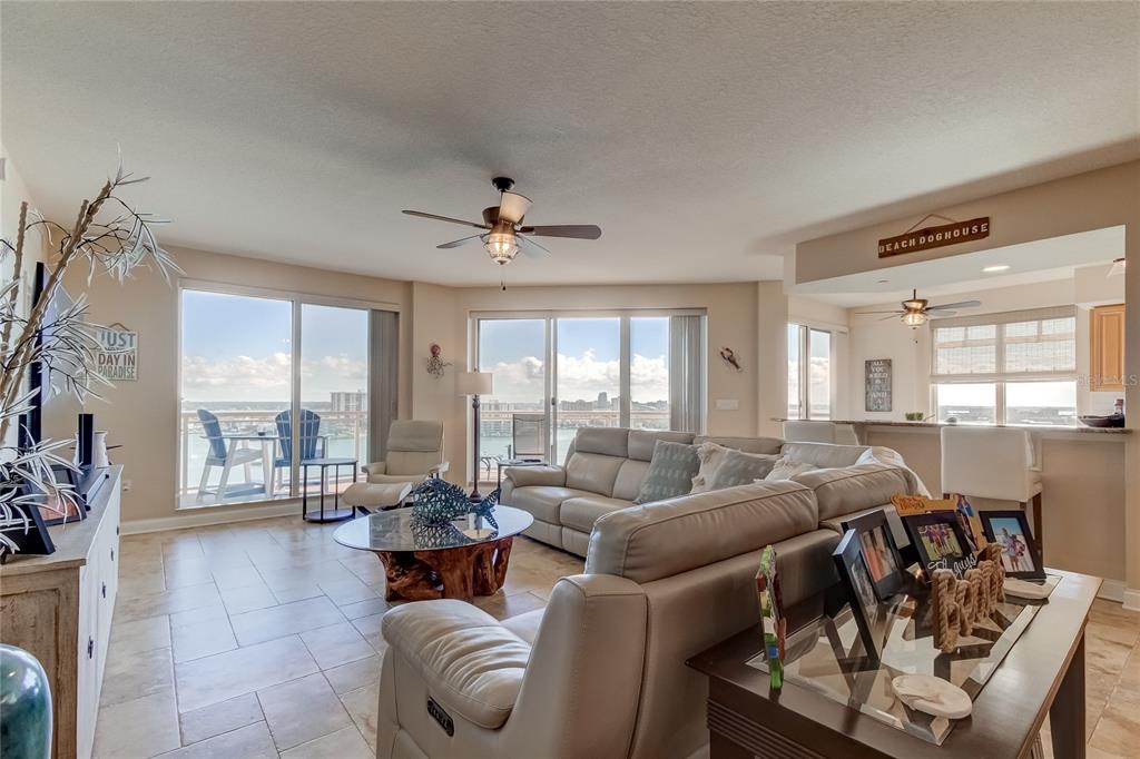 A living room with tile floors, a large sectional sofa, and a balcony overlooking water — 521 MANDALAY AVENUE UNIT 1109, CLEARWATER BEACH, FL