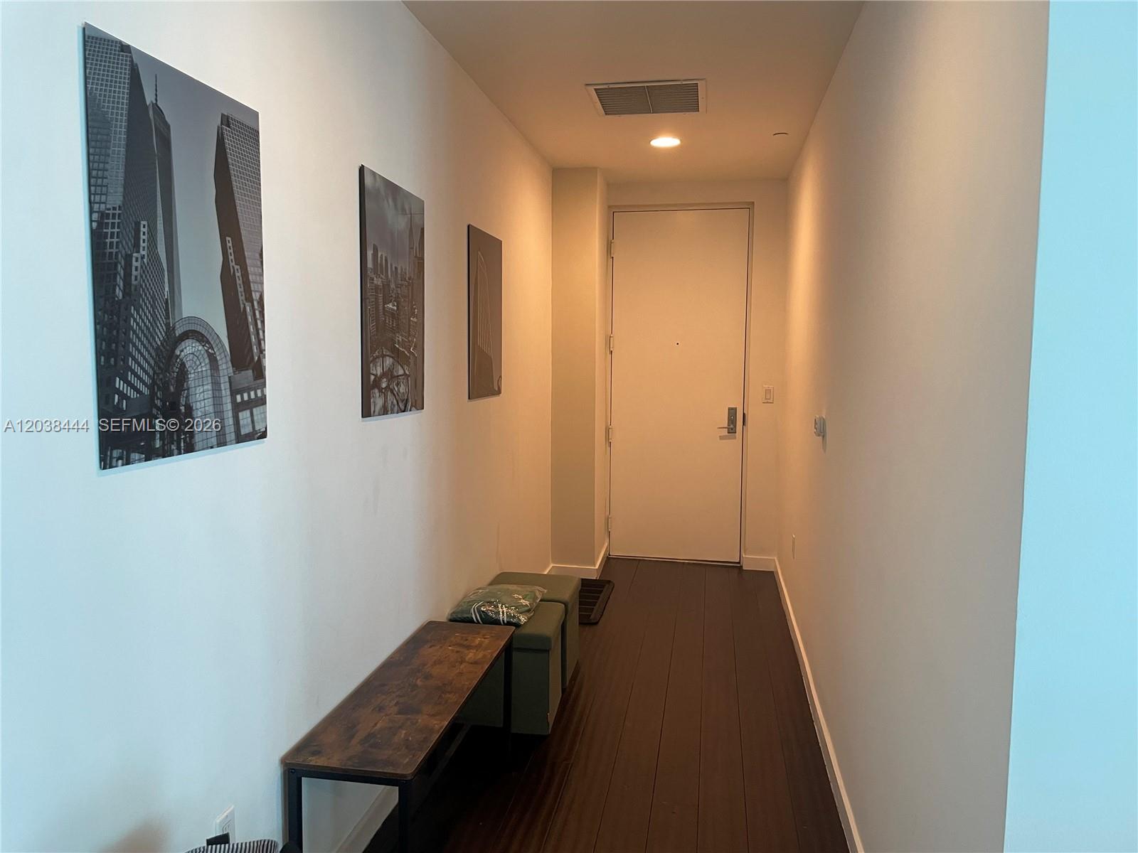 A hallway features dark wood flooring, white walls with framed art, and a wooden bench — 55 SE 6th St, Miami FL 33131, MIAMI, FL
