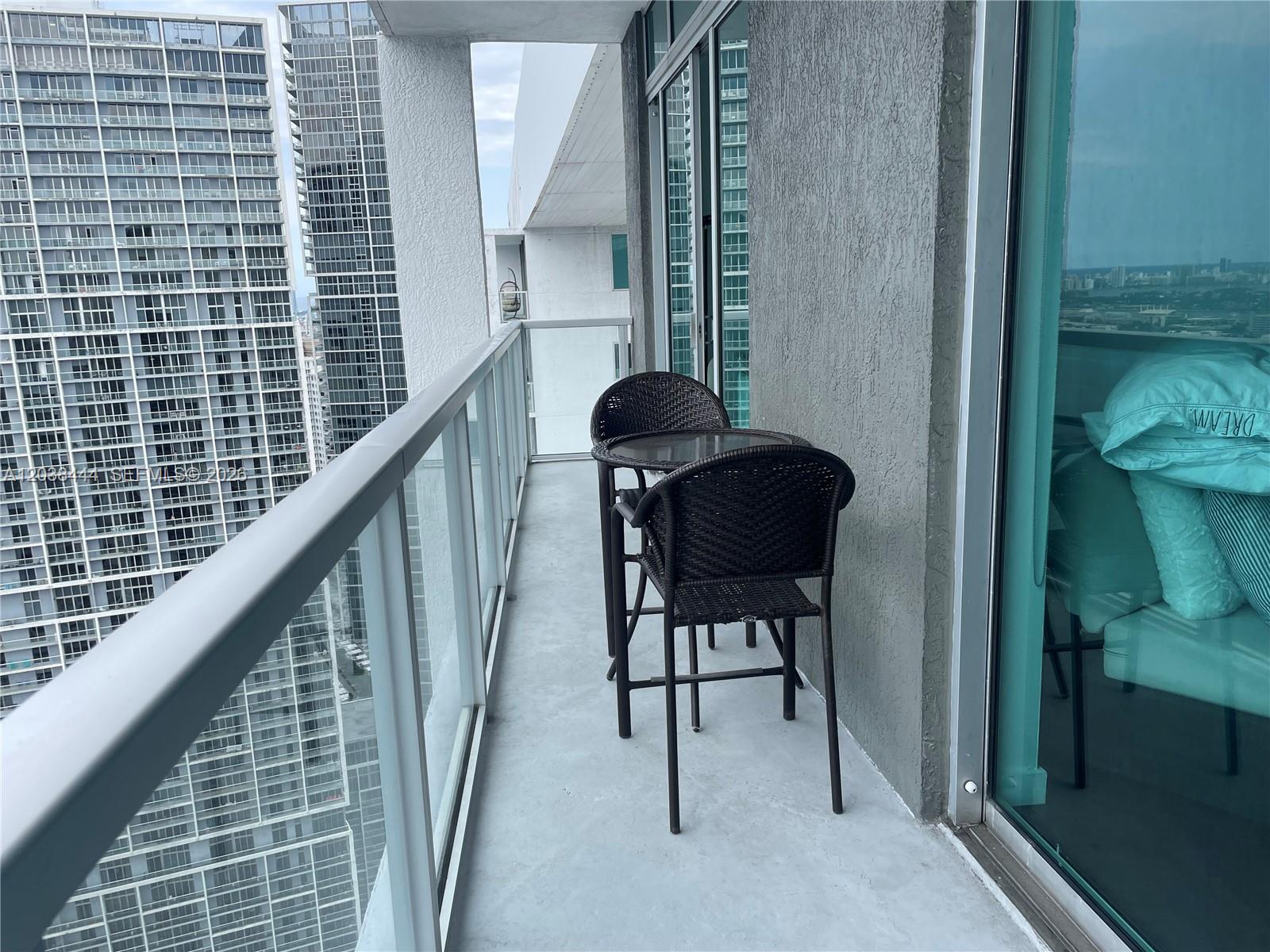 A balcony with a small table and two chairs overlooks a city skyline — 55 SE 6th St, Miami FL 33131, MIAMI, FL
