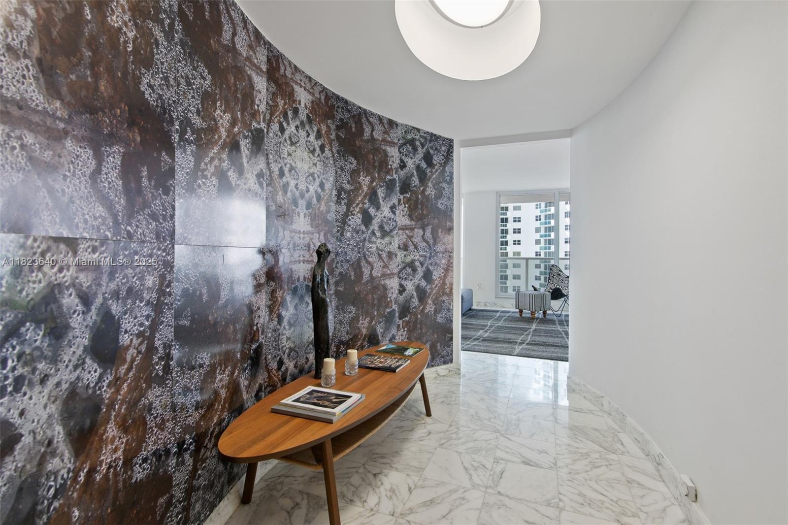 A curved hallway features a dark patterned accent wall, marble flooring, and a wooden console — 2751 S Ocean Dr # 505N, Hollywood FL 33019, HOLLYWOOD, FL