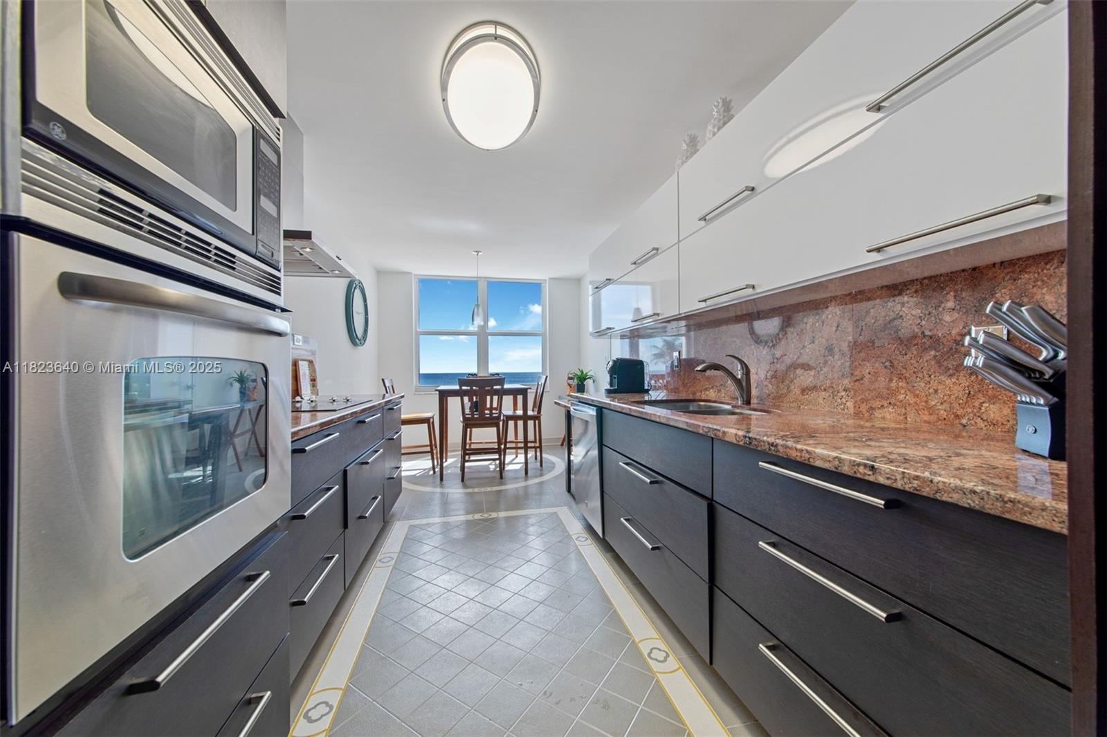 A galley kitchen features dark lower cabinets, white upper cabinets, granite countertops, and ocean views — 2751 S Ocean Dr # 505N, Hollywood FL 33019, HOLLYWOOD, FL